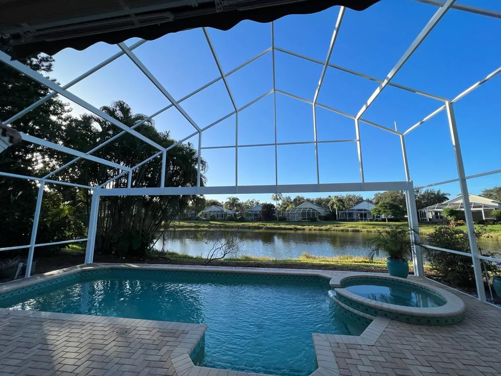 Wide panoramic pool enclosure looking out over a lake from inside the pool cage